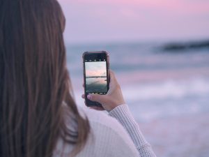 woman taking iphone photo beach